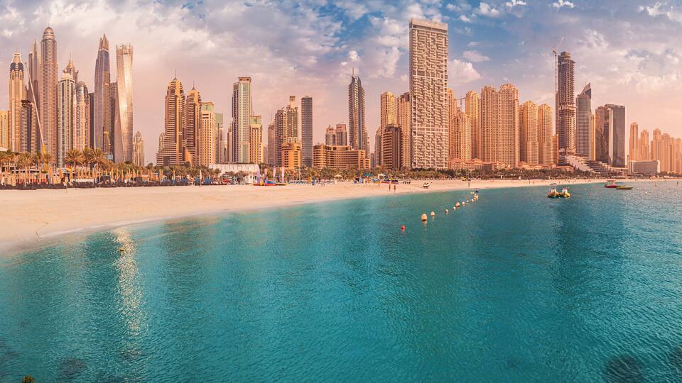 Cityscape panorama of the golden sand illuminated by the setting sun in the JBR beach area. Amazing skyscrapers and azure waters of the Persian Gulf are waiting for visitors
