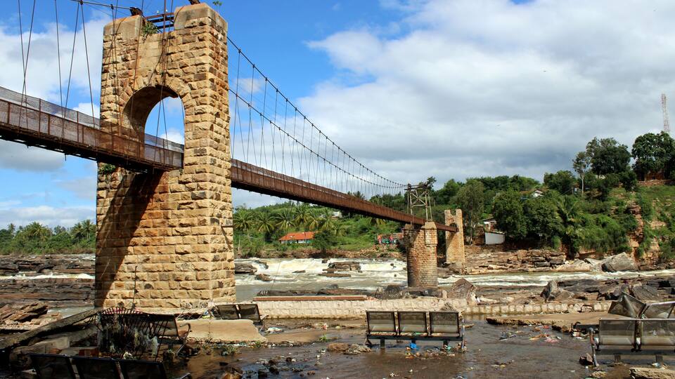 A stone bridge over a river with a bench in the foreground.