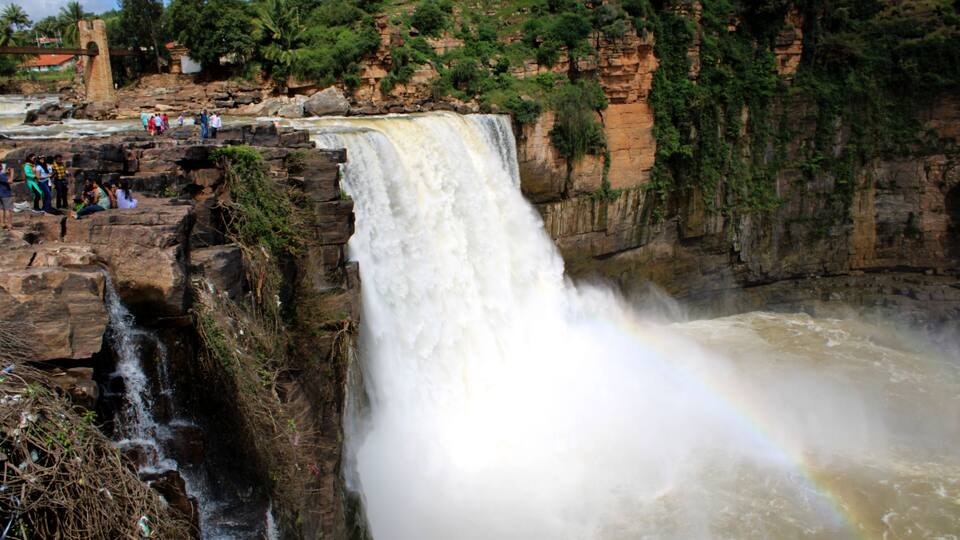A large waterfall cascading down a rocky cliff with a rainbow visible in the mist.