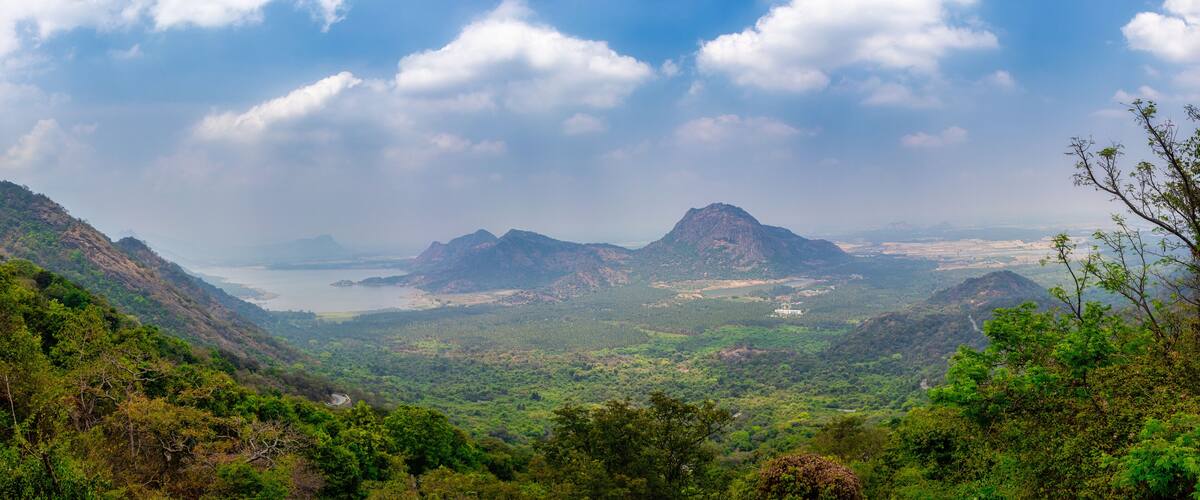 A mountainous landscape with a valley, a lake, and distant hills.