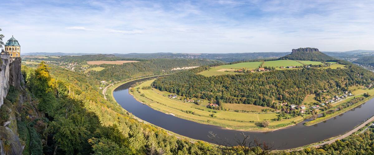 A river winding through a valley with a castle on a hill and a town along the riverbank.
