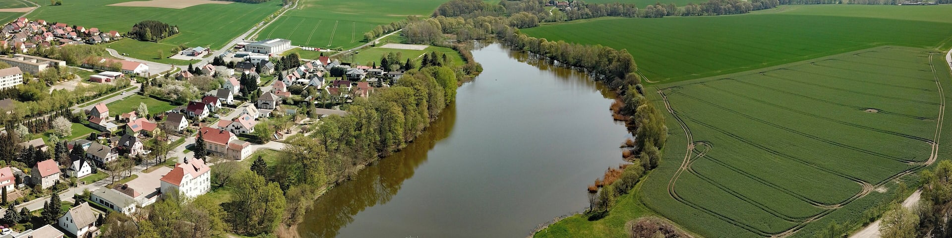 A river winding through a town surrounded by fields and forests.