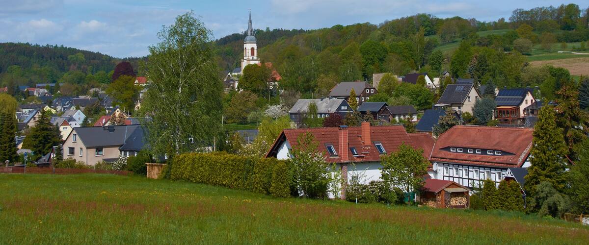 A village with houses, a church, and rolling hills.