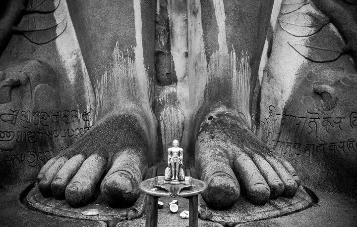 A statue of a deity with inscriptions on the hands and feet, surrounded by a circular base.