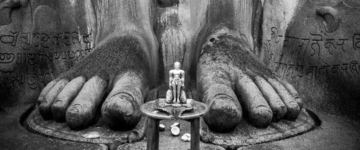 A statue of a deity with inscriptions on the hands and feet, surrounded by a circular base.