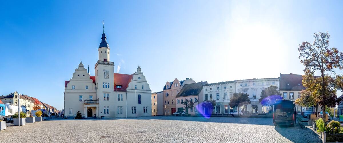 A historic church with a tall spire, cobblestone square, and surrounding buildings.