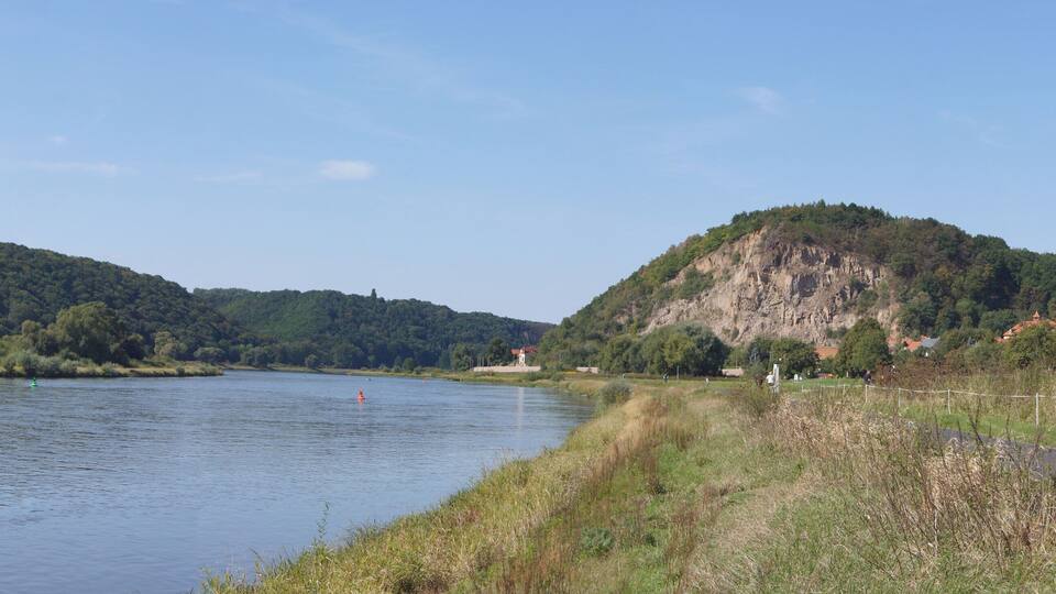 A river with a forested hill on the left and a rocky hill on the right.