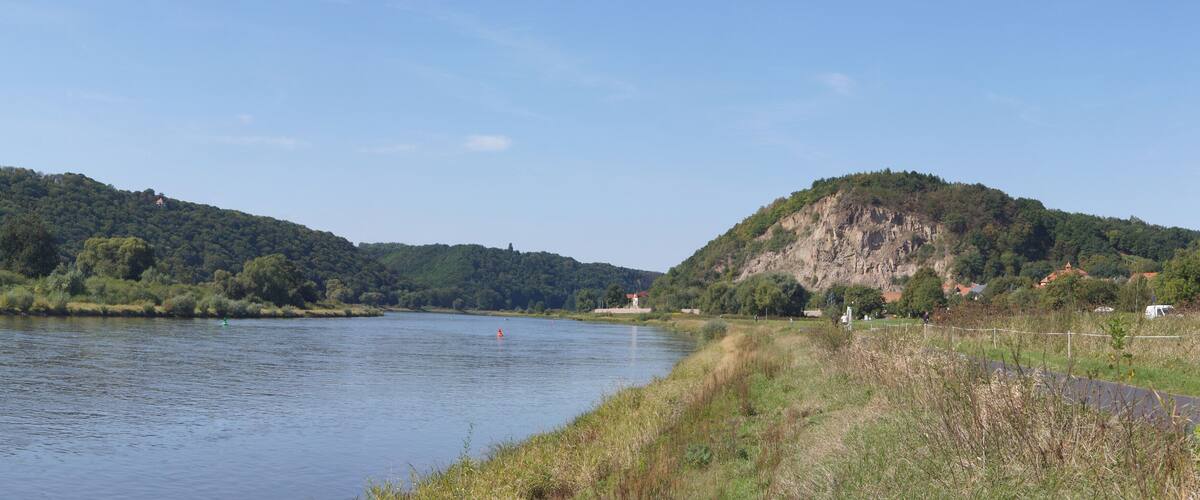 A river with a forested hill on the left and a rocky hill on the right.