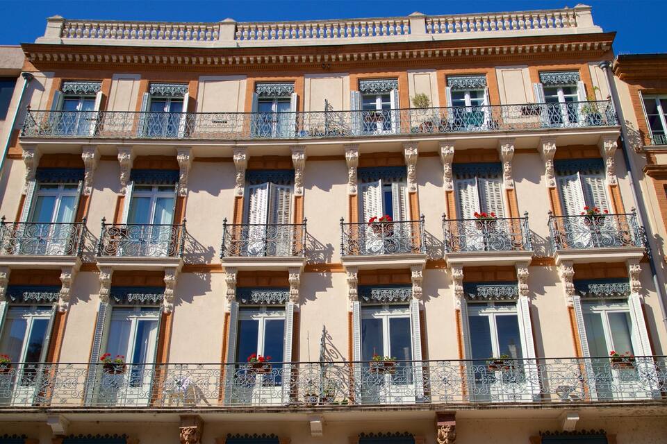 Un edificio de varios pisos con balcones ornamentados y barandillas de hierro decorativas.