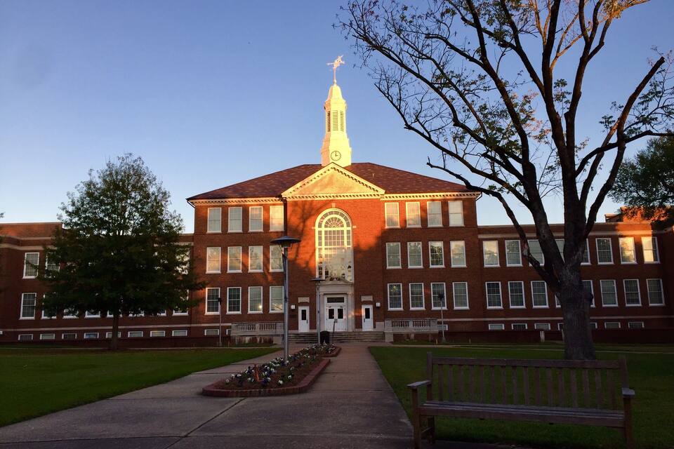 A large brick building with a prominent clock tower and arched windows.