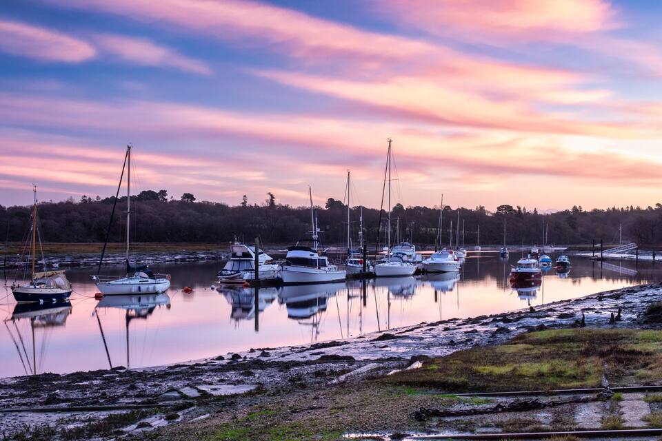 Un puerto deportivo con varios veleros amarrados al atardecer.