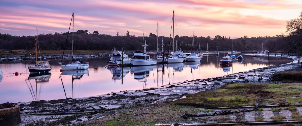 A marina with several sailboats docked at sunset.