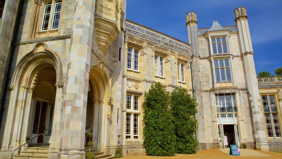 A historic building with arched doorways, a large hedge, and a sign for Castle Entrance & Gift Shop.