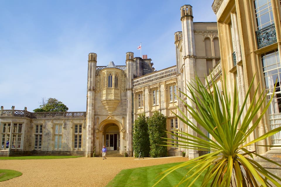 A historic building with a large entrance, a flag, and a well-maintained garden.