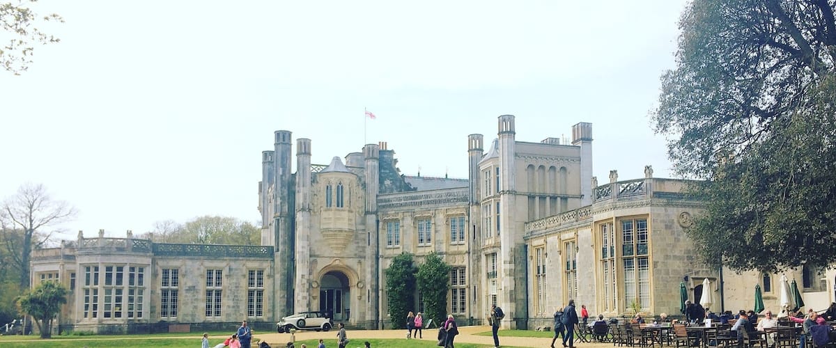 A historic building with a large lawn and people sitting and walking around.