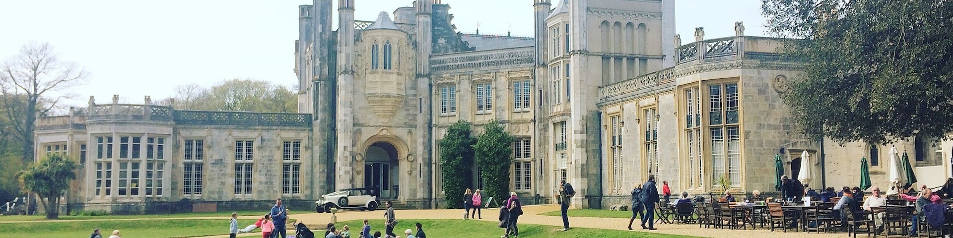 A historic building with a large lawn and people sitting and walking around.
