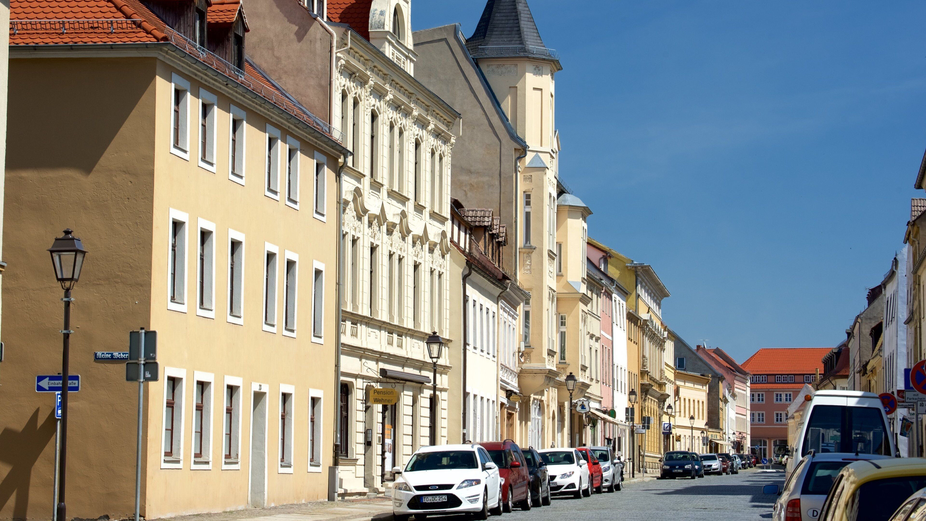 A street lined with historic buildings, parked cars, and street lamps.
