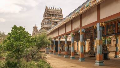 A temple with intricate carvings and a large tower in the background.