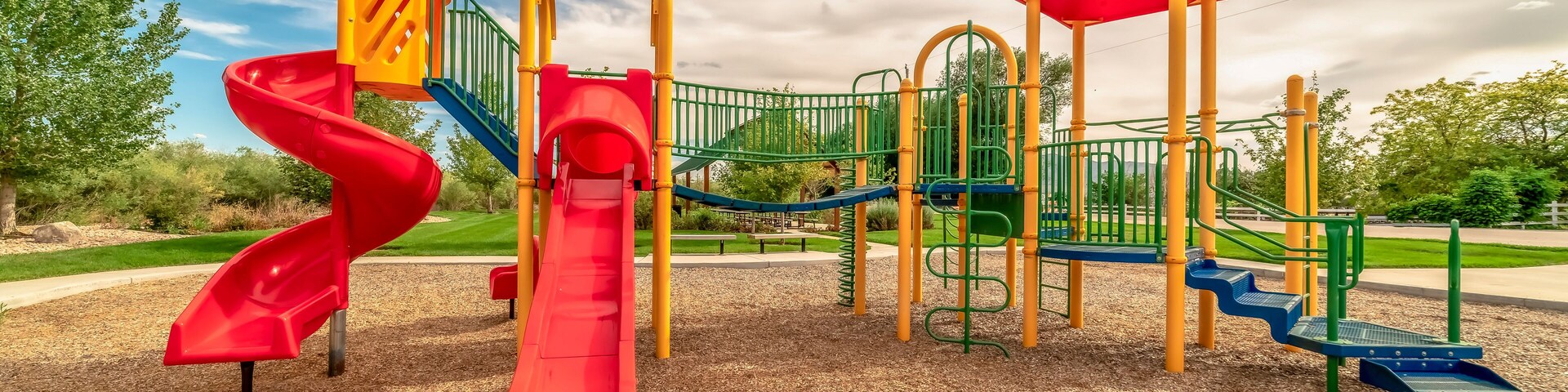 Focus on empty childrens playground at a park with red slides and climbing bars