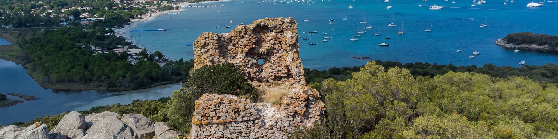 Aerial view of the remains of the square-shaped Genoese Tower of Cala Rossa overlooking the beach of Saint Cyprien in the South of Corsica, France