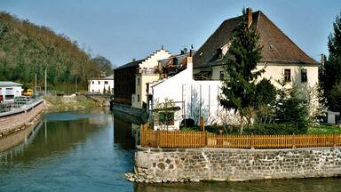 A river with buildings and a stone wall along the bank.