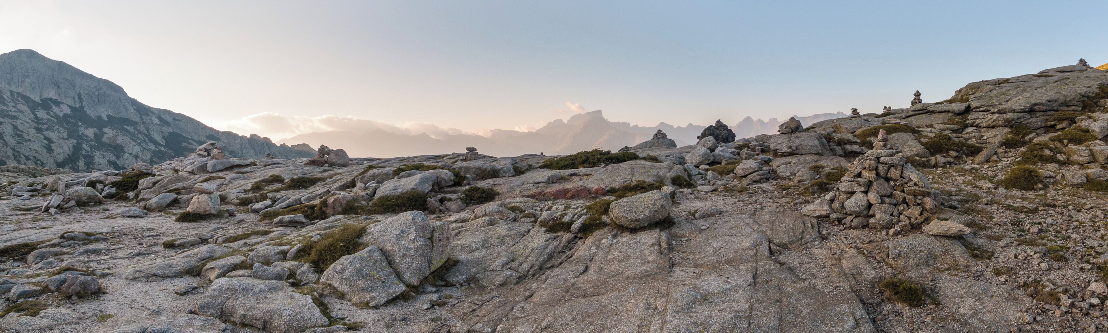 A rocky mountain landscape with large boulders and sparse vegetation.