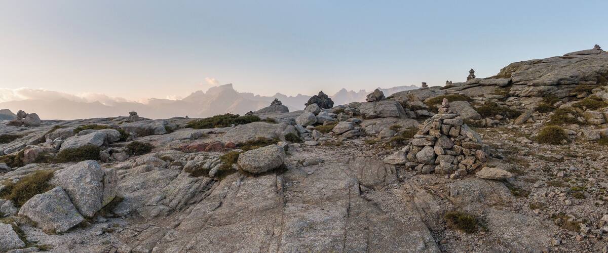 A rocky mountain landscape with large boulders and sparse vegetation.