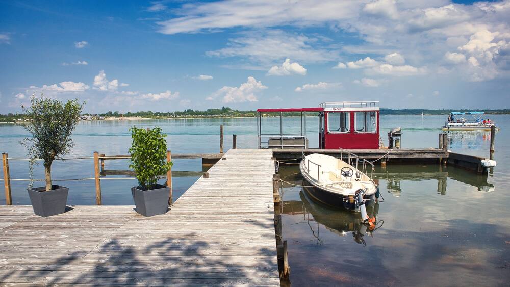 Idyllische Marina am Seeufer mit Holzsteg, Motorboot und Wolkenhimmel im Sommer, Hainer See (bei Neukieritzsch/Kahnsdorf), Landkreis Leipzig, Sachsen, Deutschland