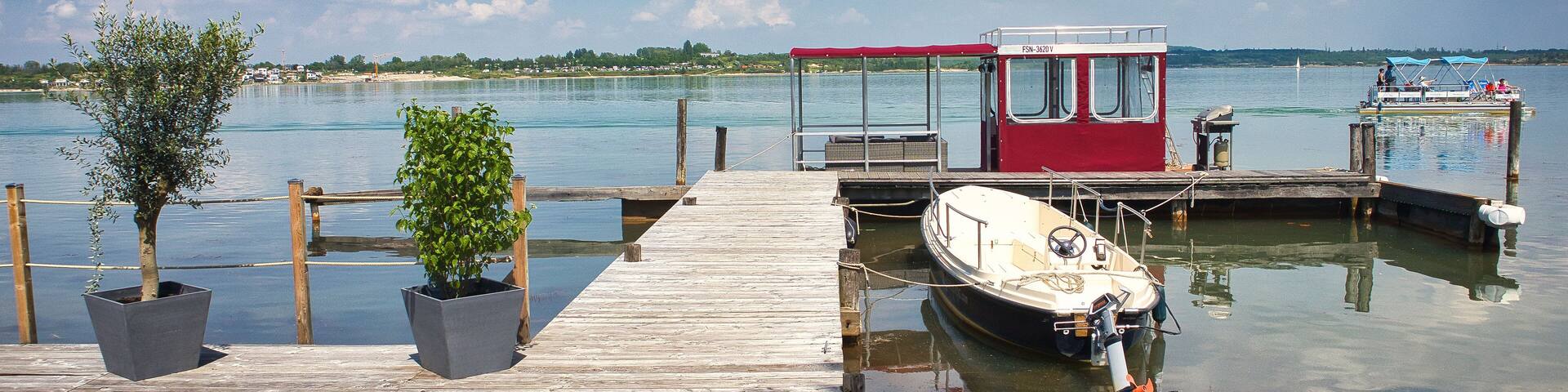 Idyllische Marina am Seeufer mit Holzsteg, Motorboot und Wolkenhimmel im Sommer, Hainer See (bei Neukieritzsch/Kahnsdorf), Landkreis Leipzig, Sachsen, Deutschland