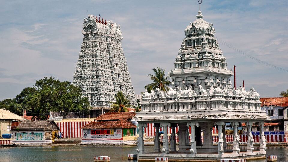 A temple complex with intricate architecture, a water body, and a small pavilion.
