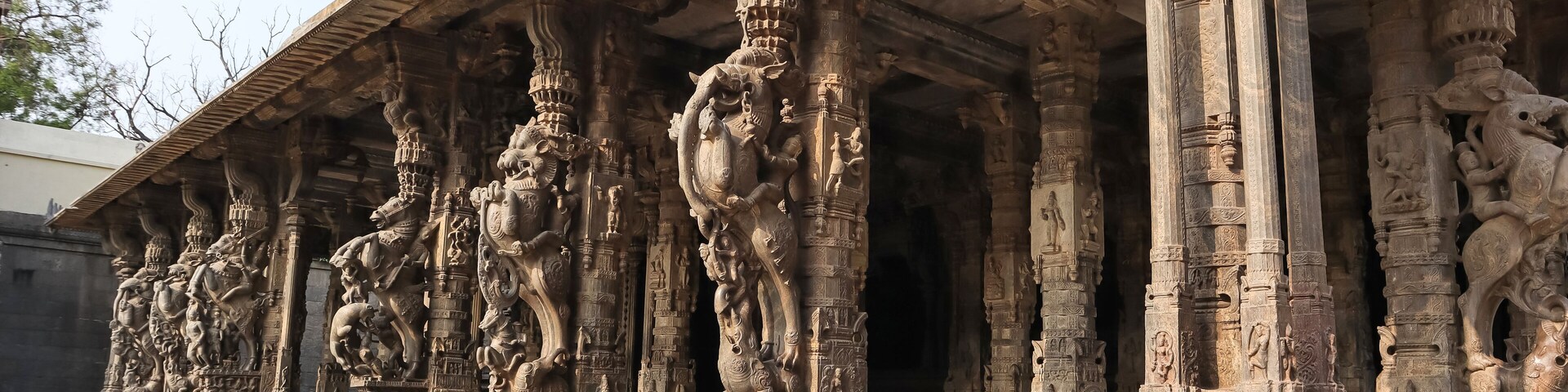 Intricately carved stone pillars with mythological figures and a temple roof structure.
