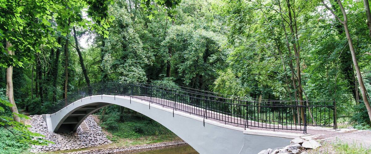 A stone bridge over a river in a forested area.