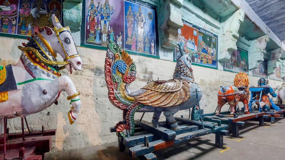 A temple interior with colorful statues of deities and religious paintings on the walls.