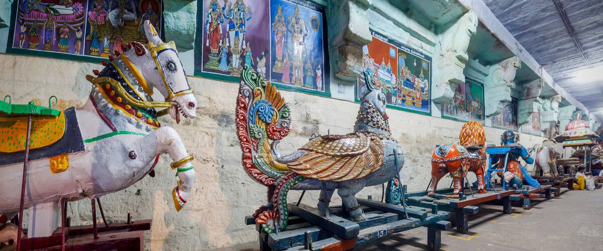 A temple interior with colorful statues of deities and religious paintings on the walls.