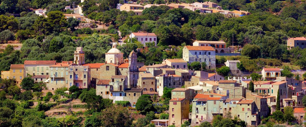 A hillside village with traditional architecture, terraced fields, and a prominent church.