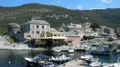 A coastal village with historic buildings, a harbor with boats, and a mountainous backdrop.