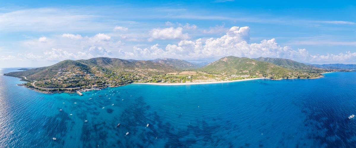 A coastal landscape with a bay, mountains, and a small town.