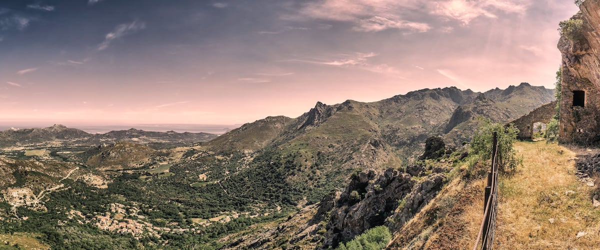 A mountainous landscape with a stone structure on a cliff.