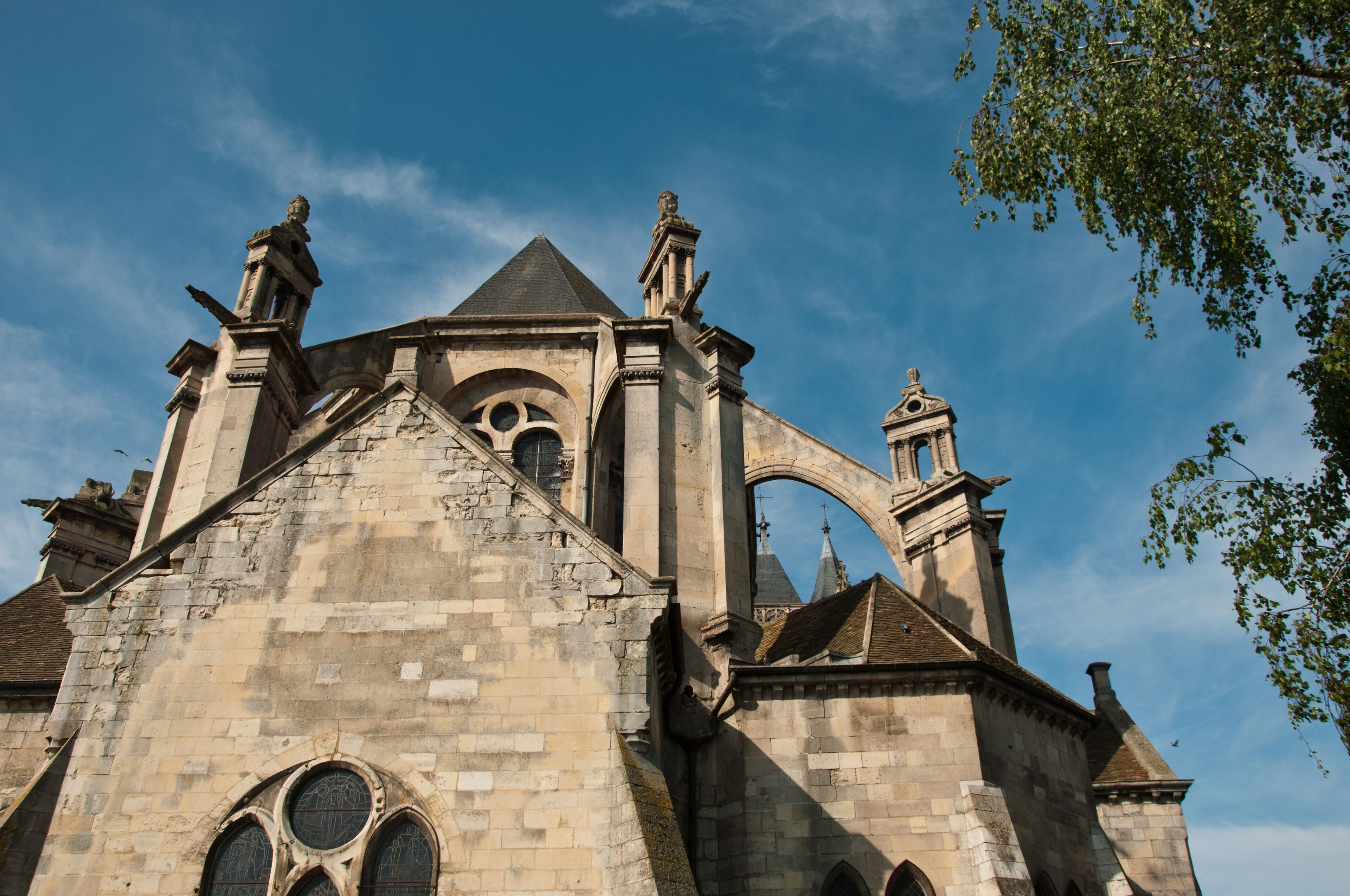 A historic church with a prominent steeple, arched windows, and statues on the roof.