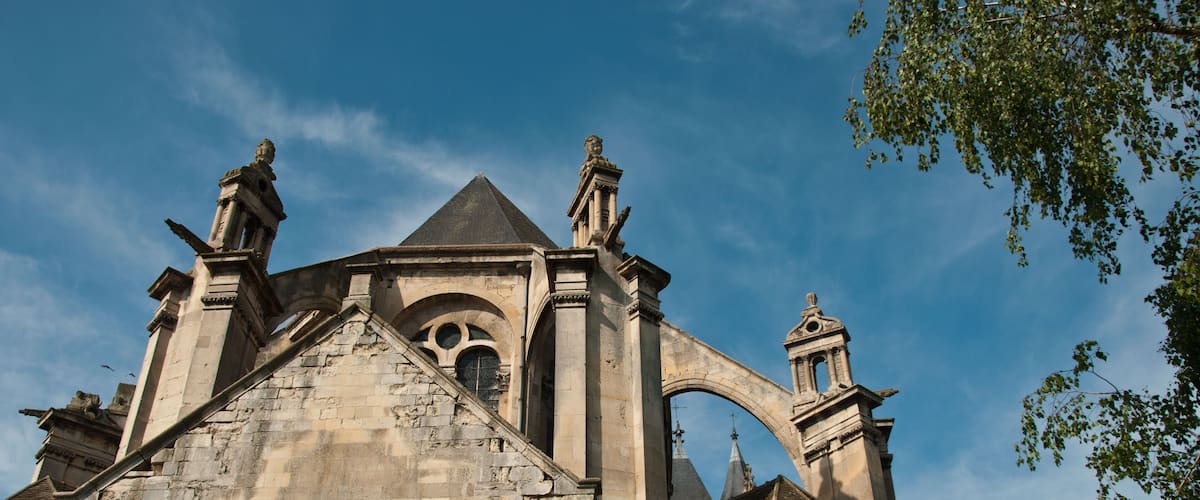 A historic church with a prominent steeple, arched windows, and statues on the roof.