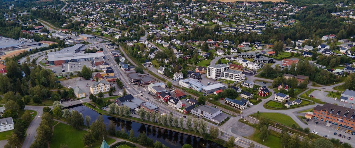 An aerial view of a town with a church, a river, and surrounding greenery.