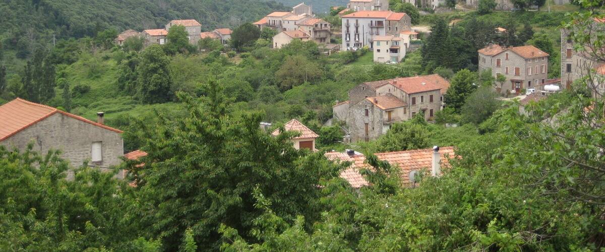 A hillside village with traditional stone houses and a mountain backdrop.
