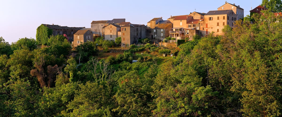 A hillside village with historic buildings and dense green foliage.