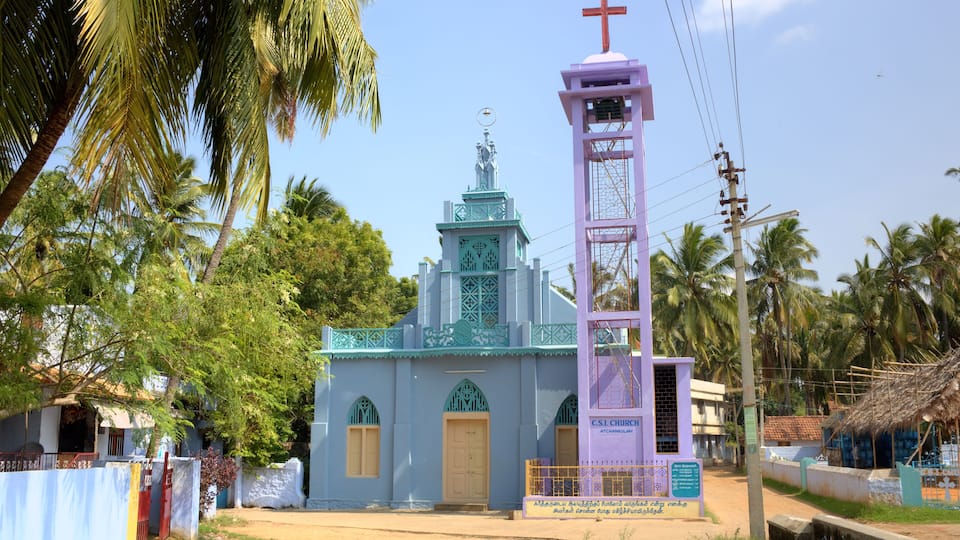 A small church with a cross on top, surrounded by palm trees.