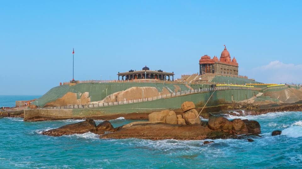 A coastal fortress with a prominent red-roofed building and a smaller structure on a rocky outcrop.