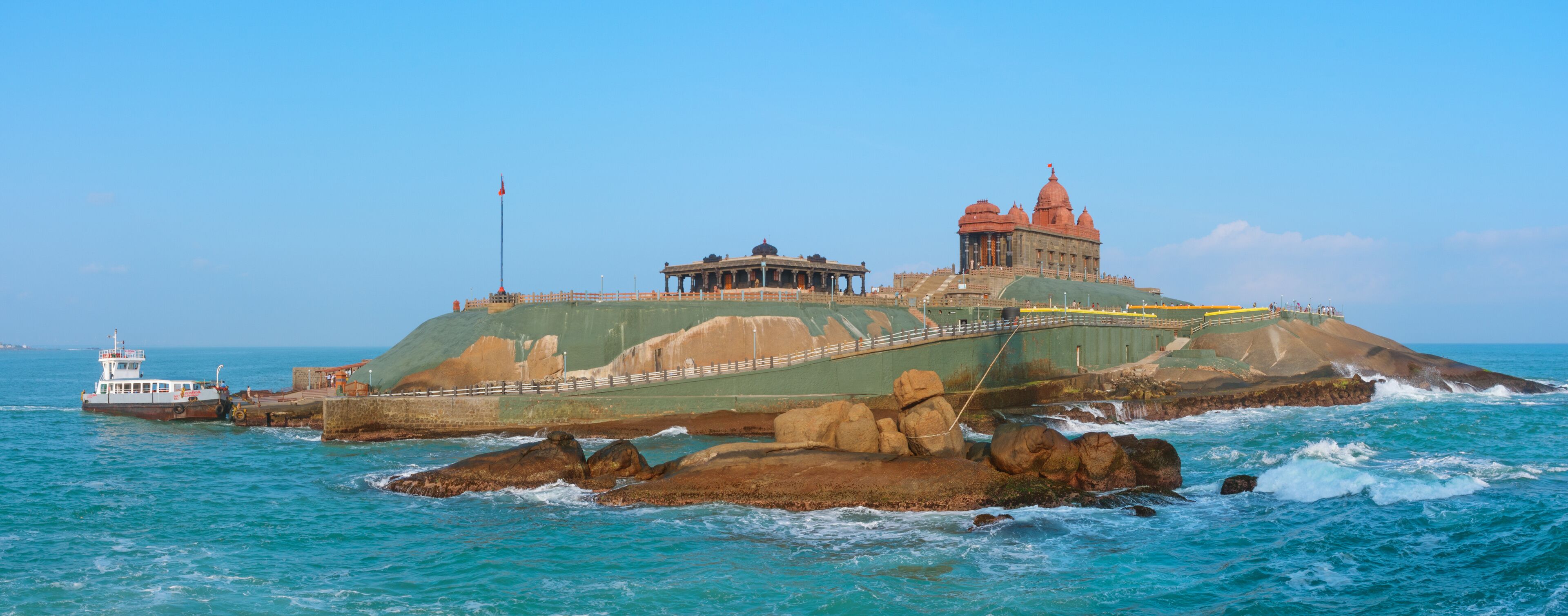 A coastal fortress with a prominent red-roofed building and a smaller structure on a rocky outcrop.