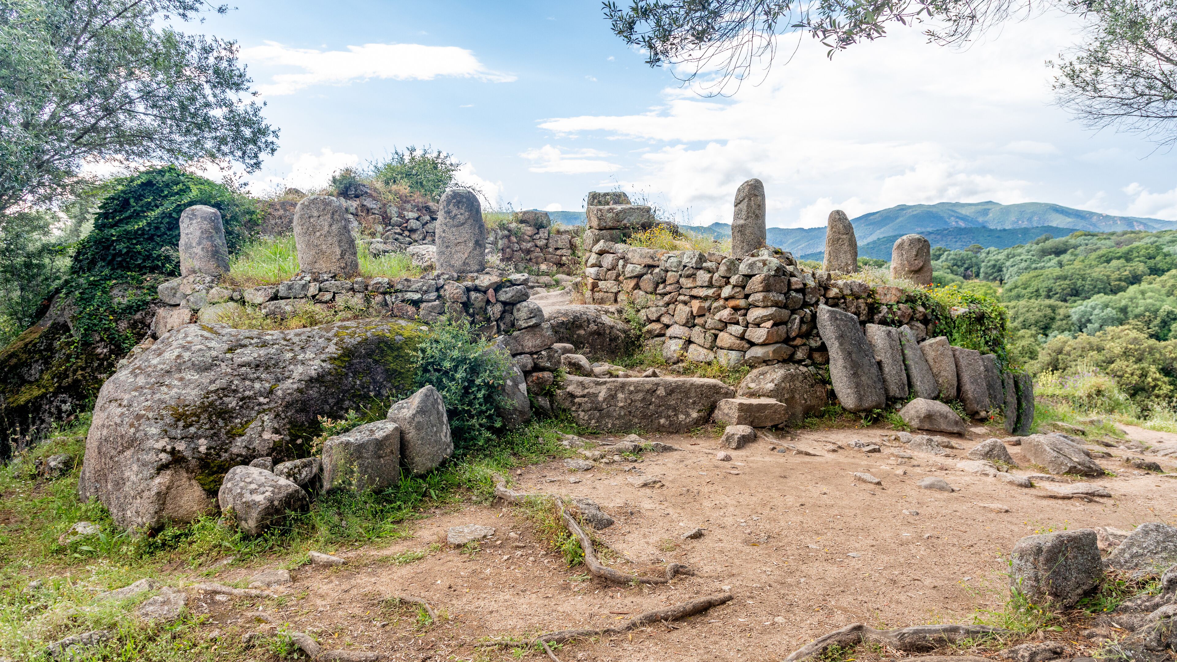 Ancient stone ruins with a mountainous backdrop.