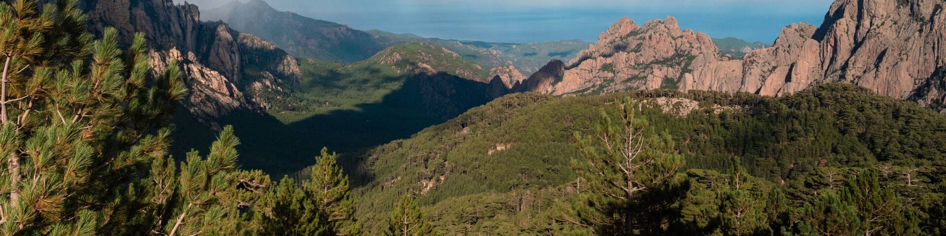 Discovering the Col de Bavella in Corsica, between the Aiguilles de Bavella, mountains, firs, a rainbow and the sea