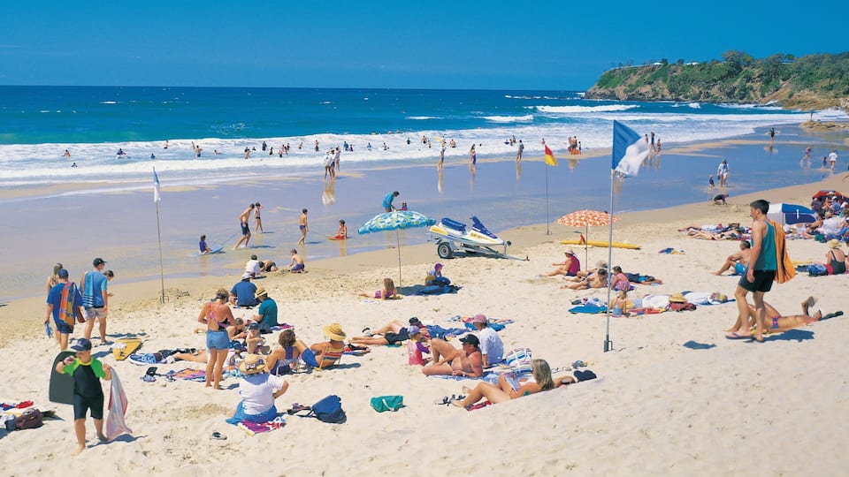 Ein überfüllter Strand mit Menschen, die sich sonnen, schwimmen und im Sand spielen.