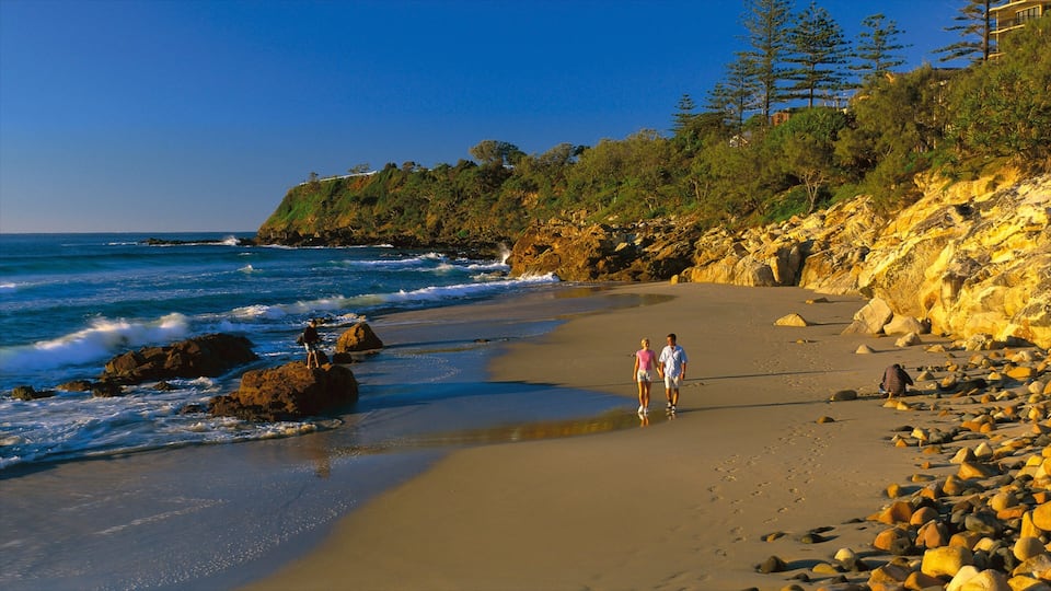Coolum Beach featuring a sandy beach and rocky coastline as well as a couple